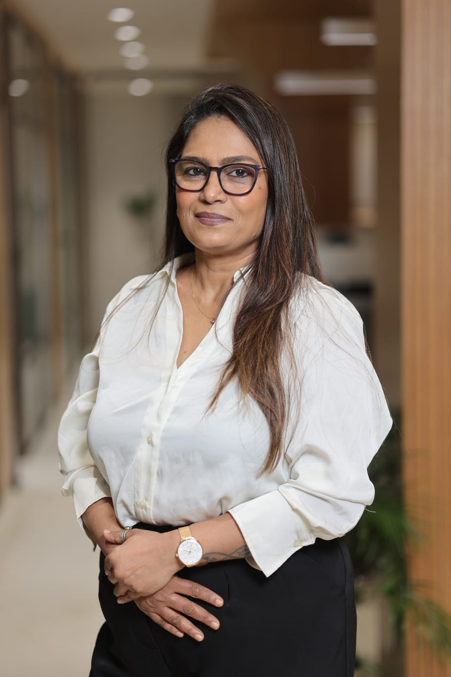 Leena Sawant standing in a bright office hallway — professional portrait